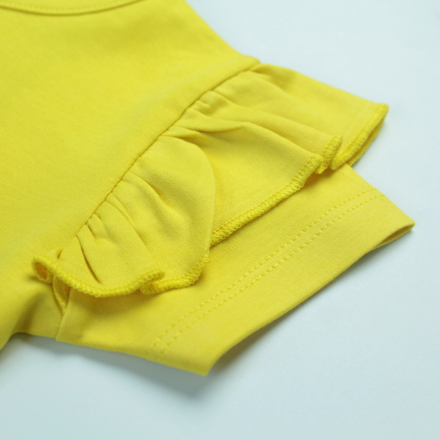 Close-up of cute cupcake design on yellow cotton T-shirt – fun and playful baby clothes for girls.