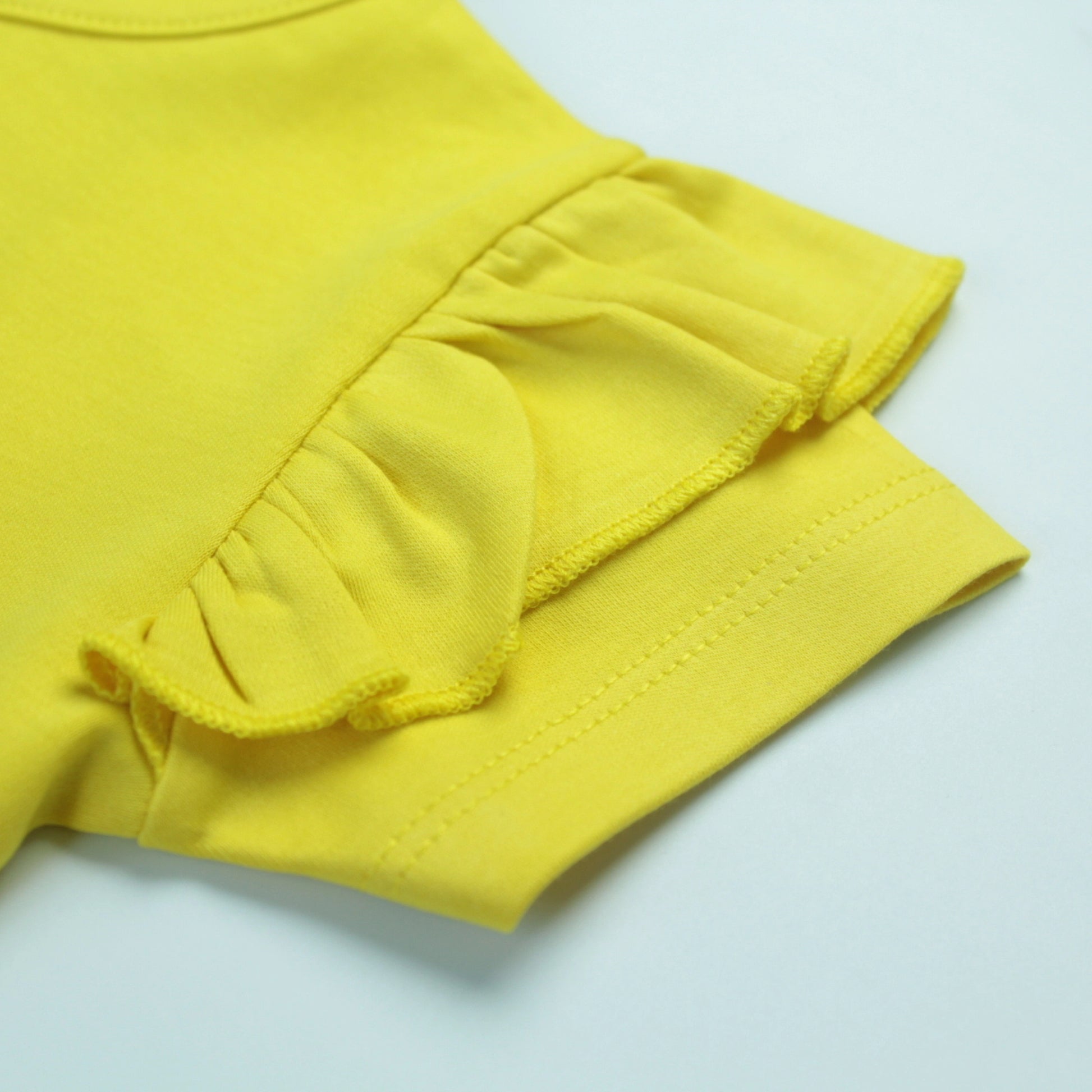 Close-up of cute cupcake design on yellow cotton T-shirt – fun and playful baby clothes for girls.