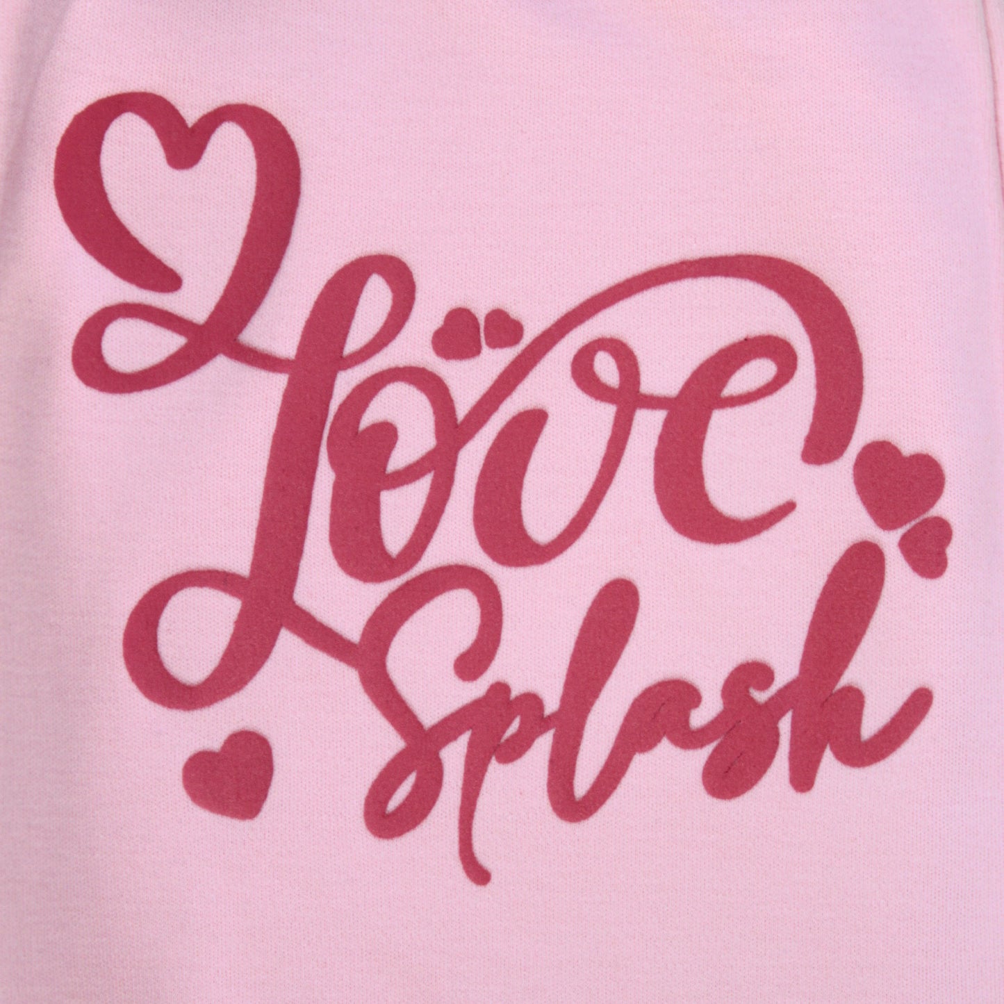 Close-up of text print and soft cotton fabric on pink joggers – premium quality clothing for infant girls