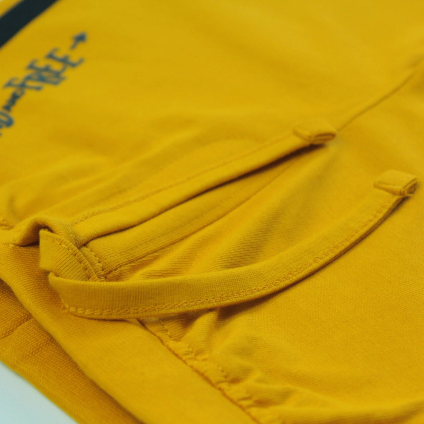 Close-up of tape detailing on yellow boys' cotton shorts – soft, breathable fabric boys' clothing ideal for everyday wear.